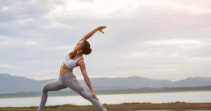Woman practicing yoga near water, promoting wellness at Shift Workspaces Denver and Shift Workspaces Littleton.