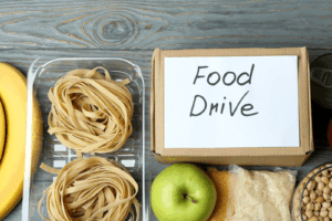 image of fresh pasta, apple, and sandwich with a box labeled food drive