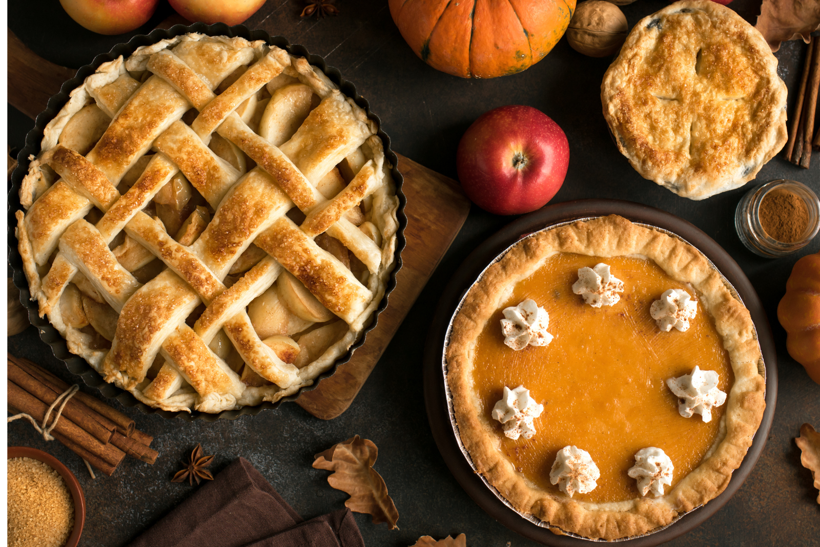 overhead view of a traditional apple pie and pumpkin pie surrounded by fall items