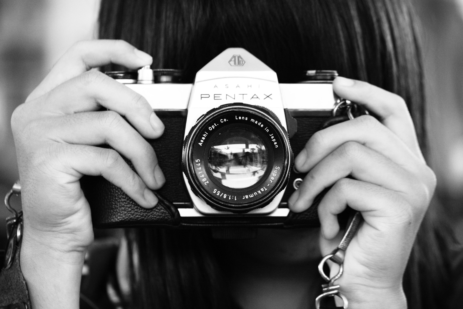 black and white image of a woman using a pentax camera