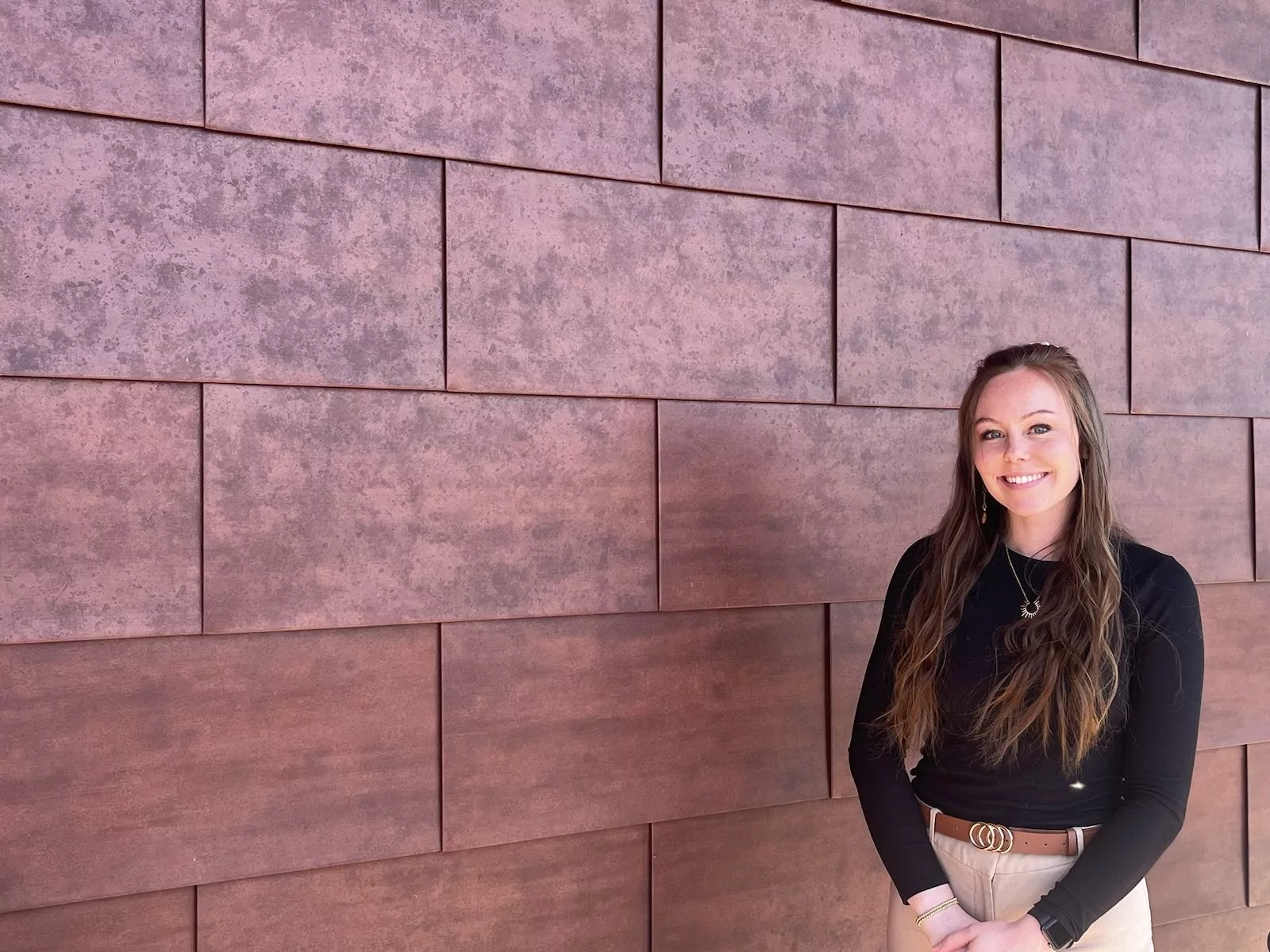 Summer Sousa smiling against a textured wall at Shift Workspaces Denver and Shift Workspaces Littleton.
