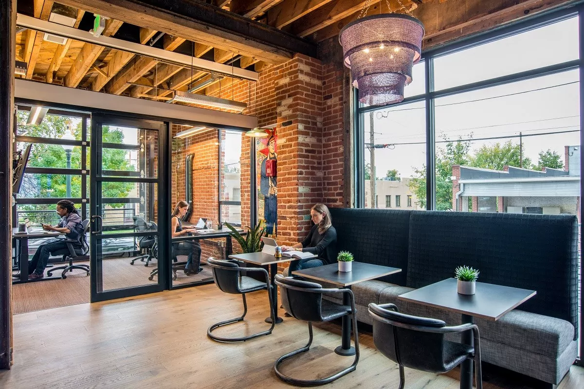 Dedicated desk and kitchen seating at Shift Workspaces Denver and Littleton with brick walls and large windows