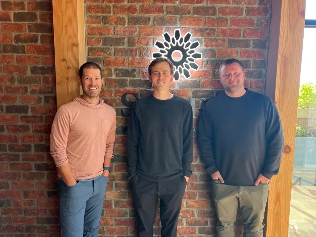 Three members of the Playermaker team smiling in front of a brick wall at Shift Workspaces Denver or Shift Workspaces Littleton.