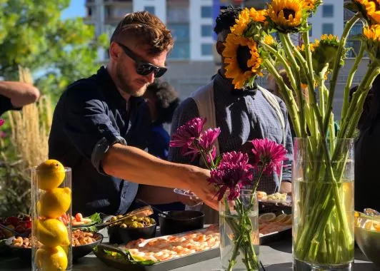 Outdoor networking event at Shift Workspaces with a vibrant food spread, fresh flowers, and guests enjoying the atmosphere