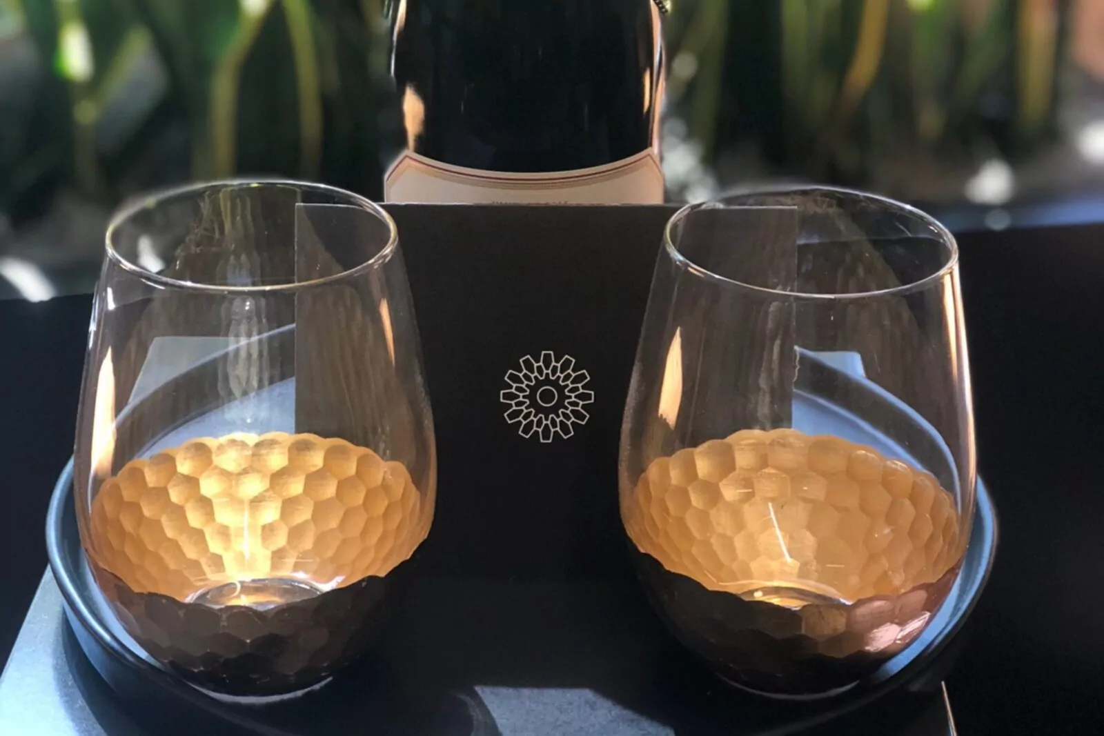 Close-up of two elegant glasses with golden accents, set on a tray with a Shift Workspaces logo