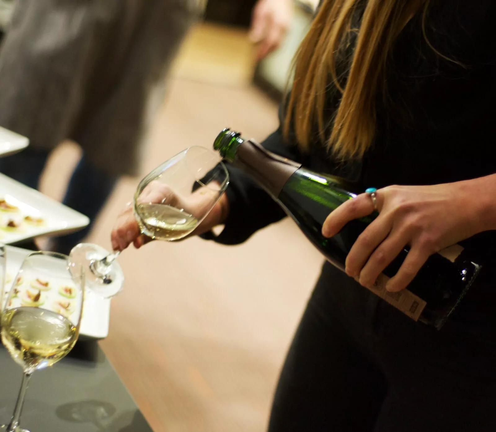 Woman pouring white wine at a Sommelier Tasting event hosted by Shift Workspaces Denver and Shift Workspaces Littleton.