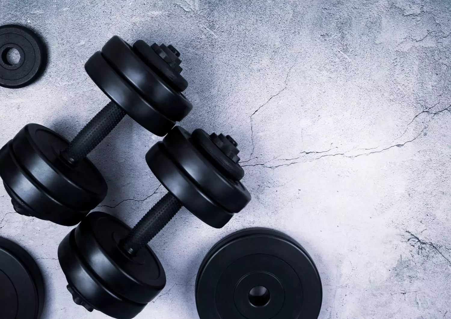 Black dumbbells on concrete background promoting fitness at Shift Workspaces Denver and Shift Workspaces Littleton.