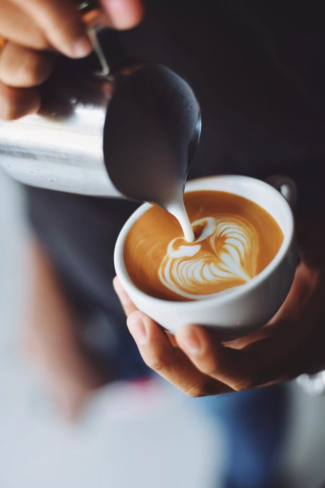 Barista pouring steamed milk into a latte with heart-shaped art at Shift Workspaces Denver and Littleton