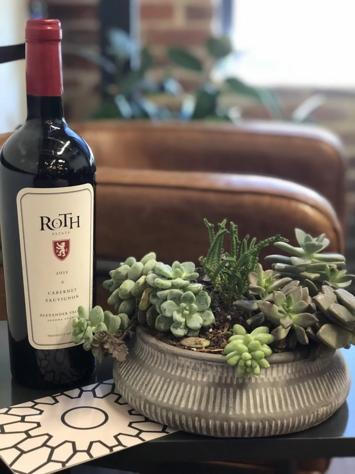 Cozy lounge setting at Shift Workspaces featuring a bottle of red wine and a stylish succulent arrangement