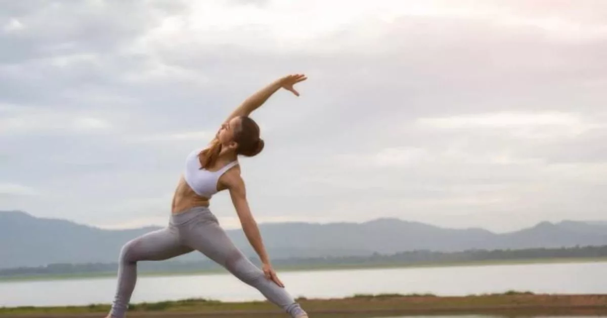Woman practicing yoga near water, promoting wellness at Shift Workspaces Denver and Shift Workspaces Littleton.